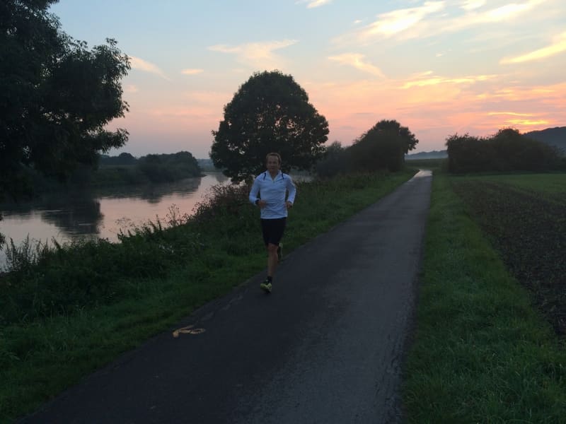 Peer hardlopend langs de Weser bij zonsondergang